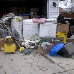 Soaked, wet personal items sitting in a driveway, including a washer and dryer in Roundup.