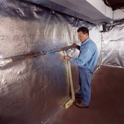 Installation of a radiant heat and vapor barrier on a basement wall in Worden