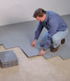 Contractors installing basement subfloor tiles and matting on a concrete basement floor in Hardin, Montana